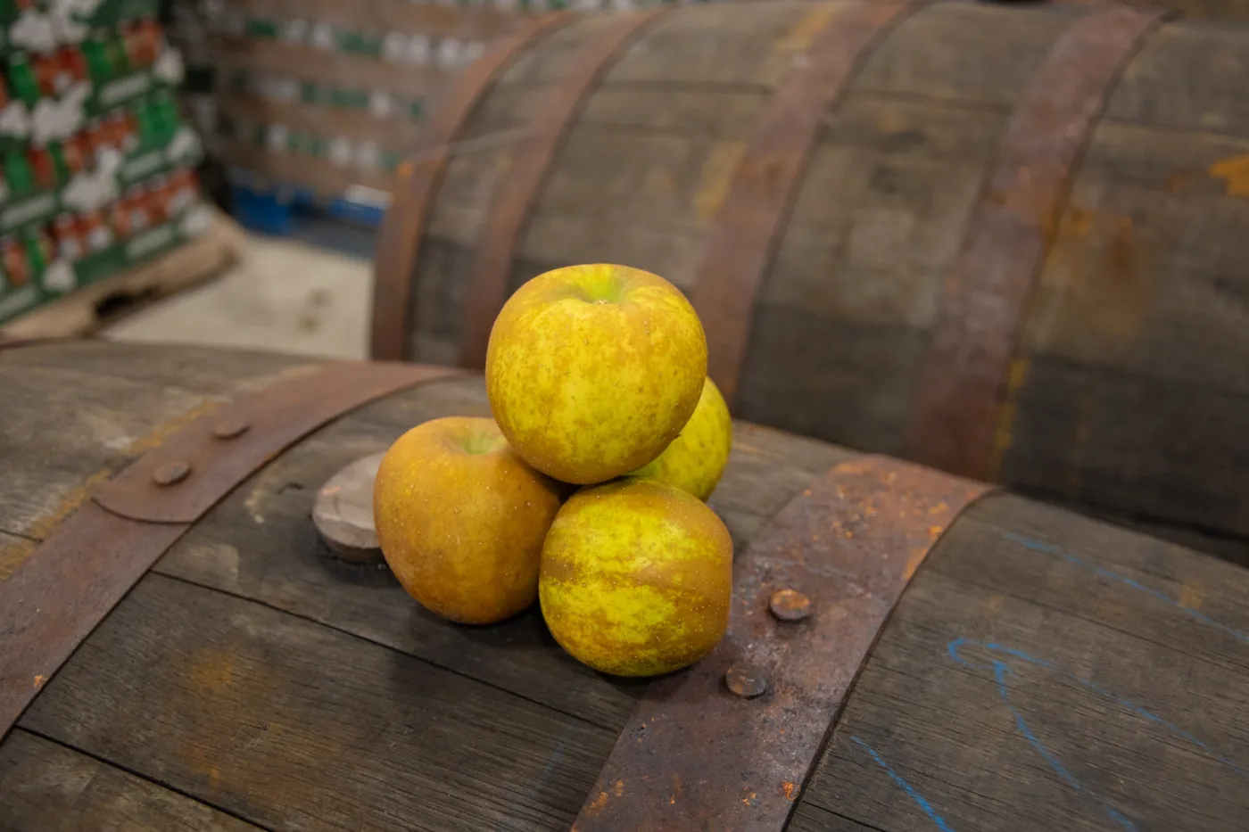 Four russeted Swayzie apples stacked in a small pyramid on top of a weathered oak barrel.